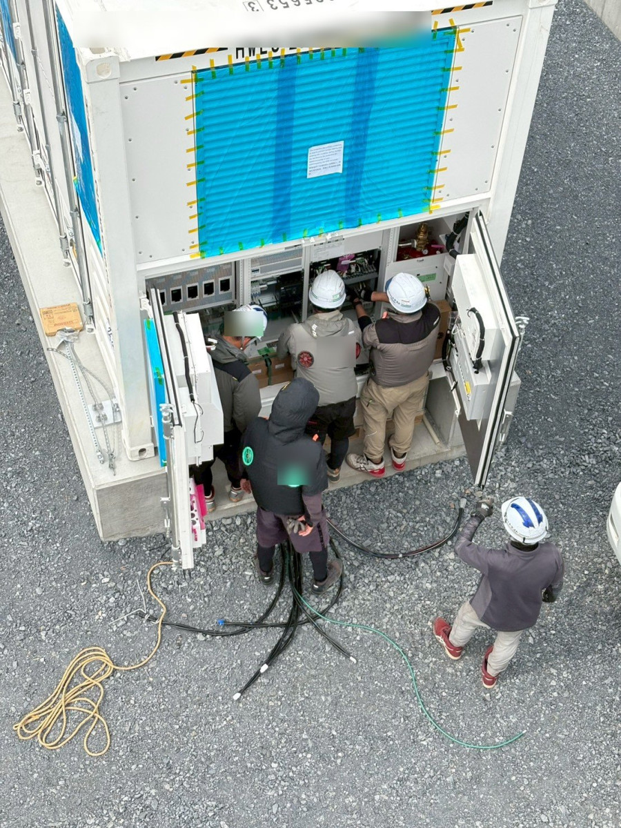 コンテナの盤の前で配線を確認する作業員