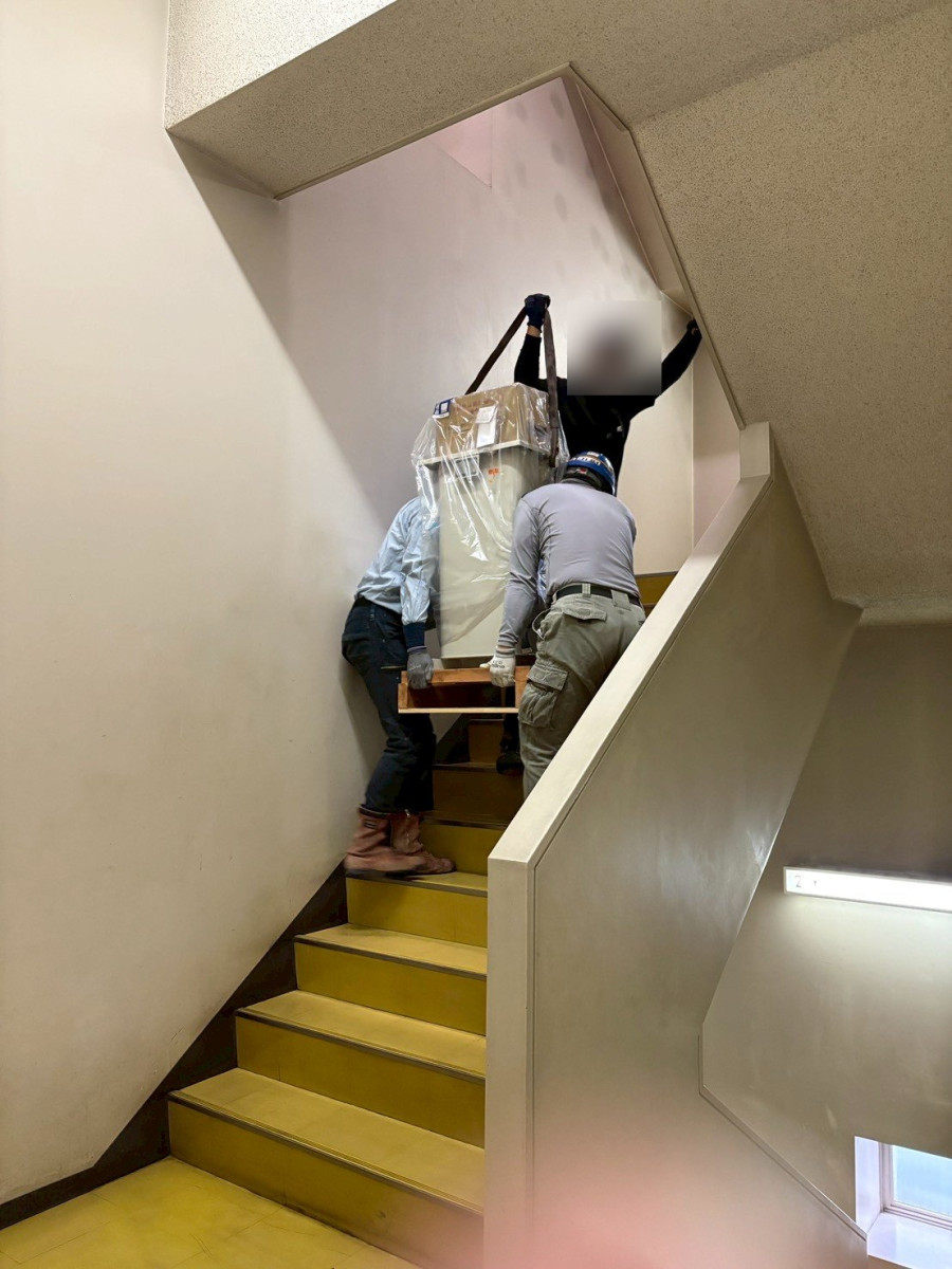 新しいコンデンサを階段で運び上げている様子